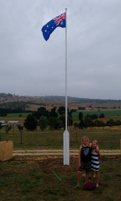 RUN IT UP THE FLAGPOLE: Sisters Sami and Anna stood beneath their flag with Mount Panorama as a backdrop on Australia Day.