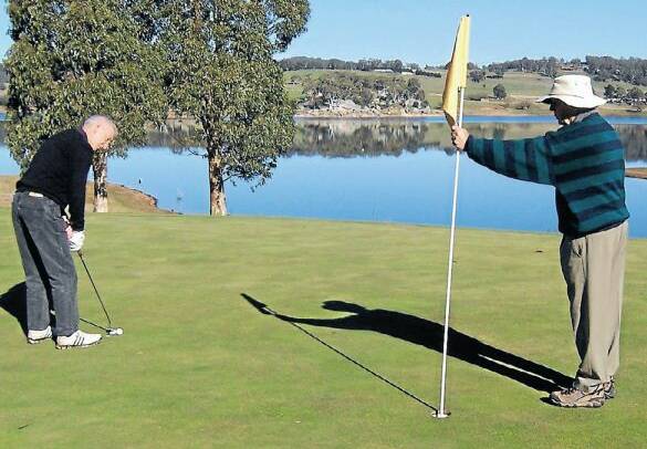 Birthday boy Bob Slattery putting out on the 5th hole with Bob Bearup attending the flag.