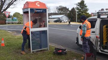 Telstra technicians conducting maintenane on a public telephone box.