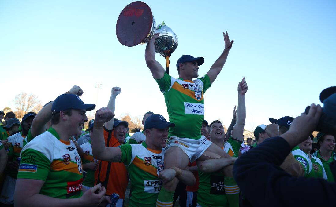 Mick Sullivan, with the premiership trophy in one hand, is lifted by his jubilant teammates after the 2017 grand final win. He captain-coached Orange CYMS to five grand finals. Photo: PHIL BLATCH