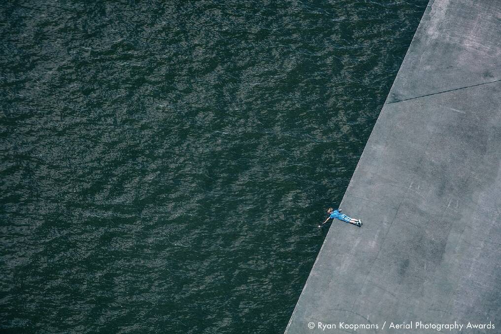 On The Edge, Amsterdam, The Netherlands. A child reaches for a plastic bag that has fallen into the Amstel River. Photo: Ryan Koopmans, Aerial Photography Awards 2020