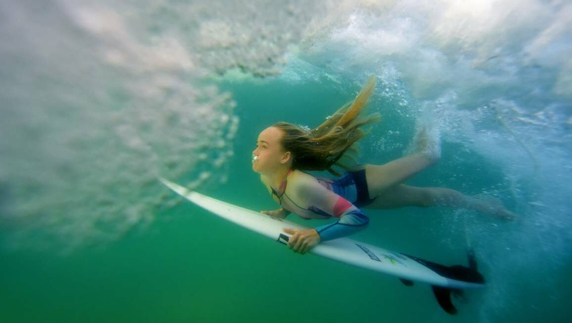 Shell Cove surfer Oceanna Rogers, 15, dives under water as she gets ready to catch her next wave. Picture: Sylvia Liber