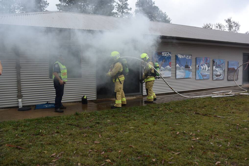 SEARCH: NSW Fire and Rescue members enter the burning building to search for two missing inmates during the emergency simulation on Tuesday.