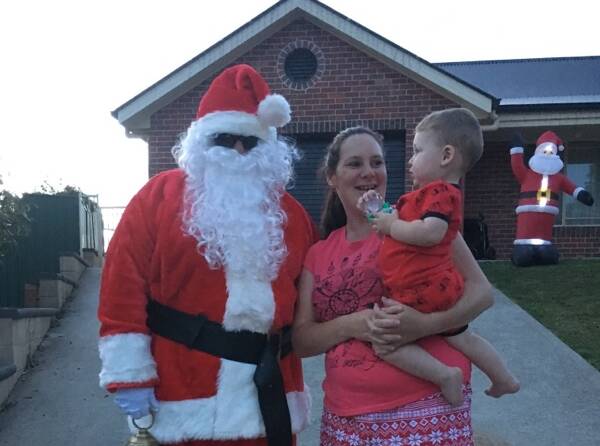 JOLLY: Santa dropped in to visit Leslie Griffiths and her son Wyatt while judging the Christmas Lights Competition.