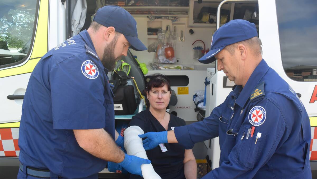 WRAPPING UP: Oberon paramedics Brendan Bourne and John Kanne demonstrate how to apply an immobilisation bandage to Christine Symington if a snake bites you on the finger.