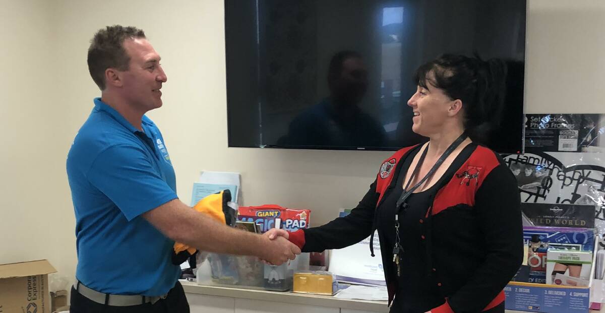 HAPPY: Oberon Tigers captain/coach Luke Branighan presents last year’s jersey to Columbia Aged Care facility service manager Jaci Newman.