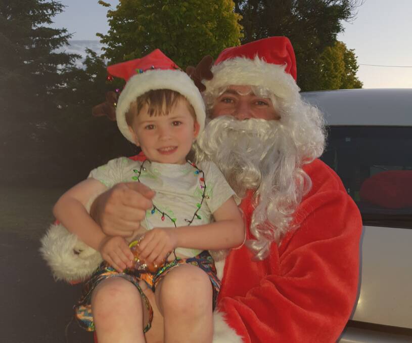 CUDDLES: Blake Hunt enjoying a close-up with Santa. The man in the red suit proved popular during the Christmas lights judging.