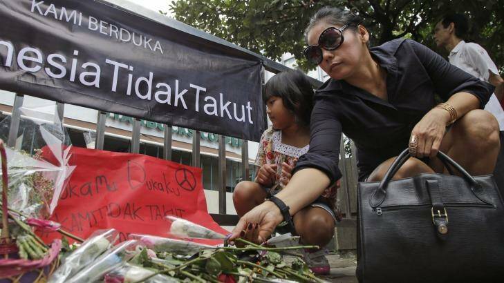 A woman lays flower outside the Starbucks cafe where Thursday's attack took place in Jakarta. Photo: Tatan Syuflana